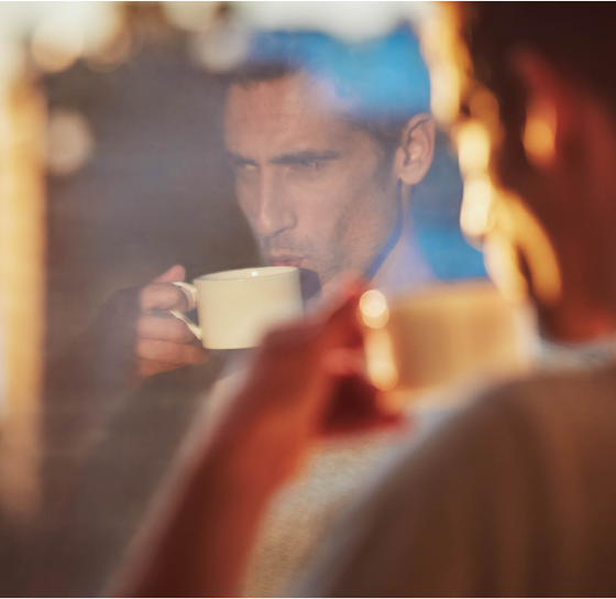 man drinking coffee and looking outside the window
